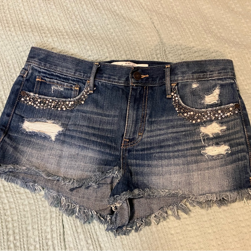 Size 10/30 Abercrombie & Fitch cutoff jean shorts with front pocket bead detail.